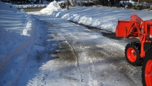 A stone driveway covered with snow and a tractor plow